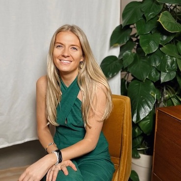 Louisa sitting on a chair in a green outfit